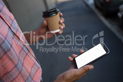 Man having coffee while using mobile phone
