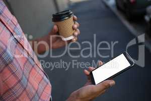 Man having coffee while using mobile phone