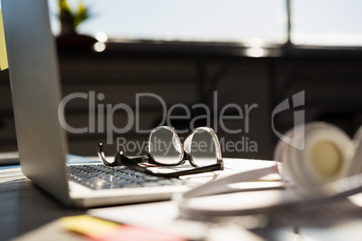 Laptop with eyeglasses by headphones on table at office