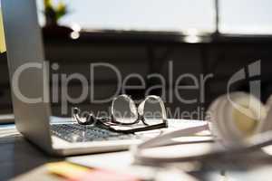 Laptop with eyeglasses by headphones on table at office