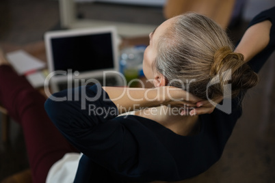 Businesswoman with hands behind head relaxing in office