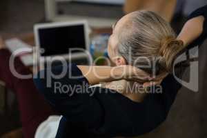 Businesswoman with hands behind head relaxing in office