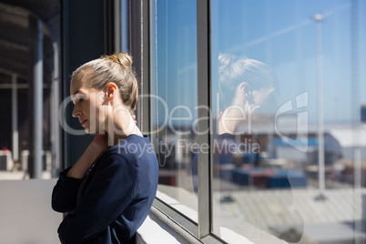 Tired businesswoman looking lown while standing by window