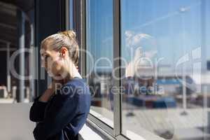 Tired businesswoman looking lown while standing by window