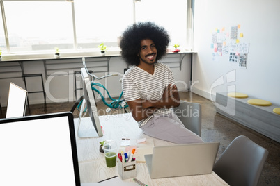 Portrait of smiling man sitting on desk at office