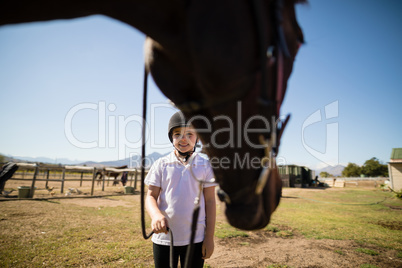 Smiling girl holding the rein of the horse in the ranch