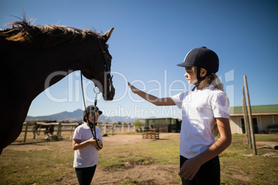 Two girls standing with a horse in the ranch