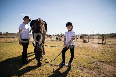 Smiling girls standing in ranch with brown house