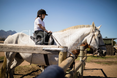 Girl sitting on the horse in the ranch