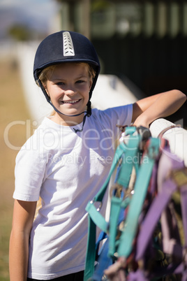 Smiling girl leaning on the fence next to horse reins and muzzle