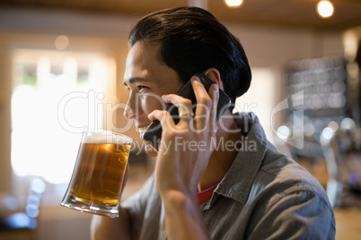 Man having beer while talking on mobile phone in a restaurant