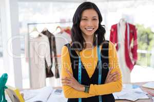Smiling fashion designer standing with arms crossed in office