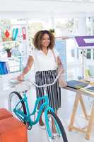 Female executive walking with bicycle in the office
