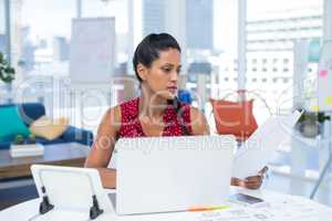 Female executive looking at documents while working at desk