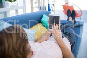 Male executive using digital tablet while relaxing on sofa