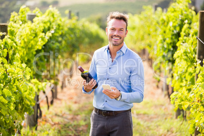 Portrait of smiling man with wine bottle using phone