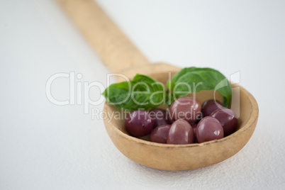 Close up of brown olives with herb in wooden ladle