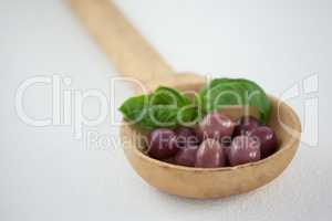 Close up of brown olives with herb in wooden ladle