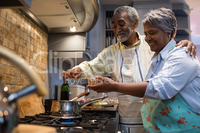 Smiling senior couple preparing food in kitchen