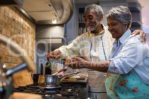 Smiling senior couple preparing food in kitchen