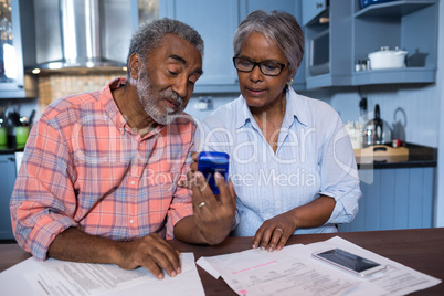 Couple using calculator in kitchen