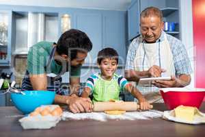 Smiling man using table while standing by father and son preparing food