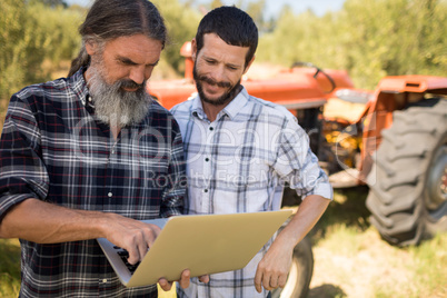 Friends discussing over laptop in farm