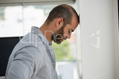 Frustrated designer leaning on wall at office
