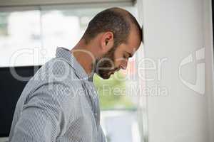 Frustrated designer leaning on wall at office