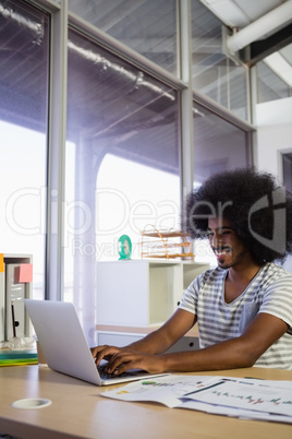 Smiling young man using laptop at office