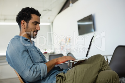 Relaxed man using laptop in office