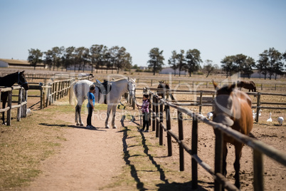Kids standing with a white horse in the ranch