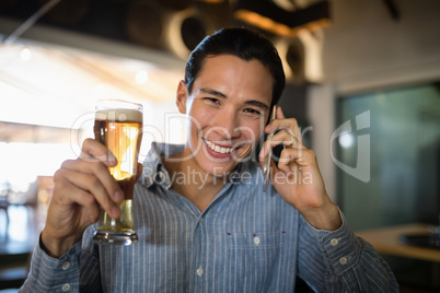 Man having beer while talking on mobile phone Man having beer while talking on mobile phone