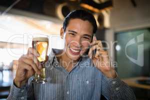 Man having beer while talking on mobile phone