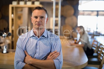 Man standing with arms crossed near bar counter