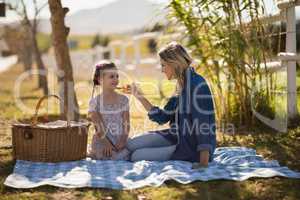 Mother feeding food to her daughter on picnic