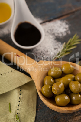 Close of olives in spoon by oil on table