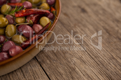 Cropped image of olives with oil and chili pepper in container