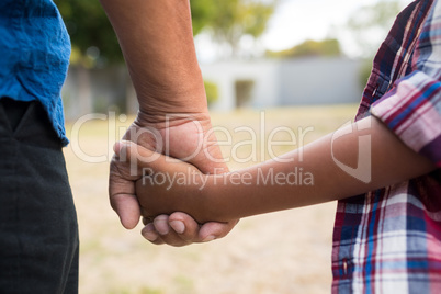 Cropped image of boy and grandfather holding hands
