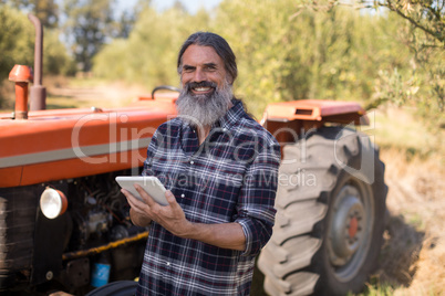 Portrait of happy man using digital tablet in olive farm