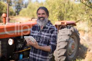 Portrait of happy man using digital tablet in olive farm