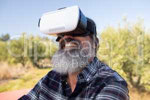 Happy man using virtual reality headset in olive farm