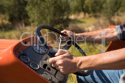 Mid section of man driving tractor in olive farm