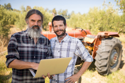 Portrait of happy friends using laptop in farm