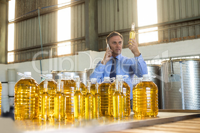 Manager talking on mobile phone while examining olive oil