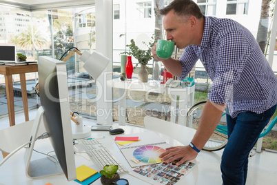 Designer looking at computer while having drink