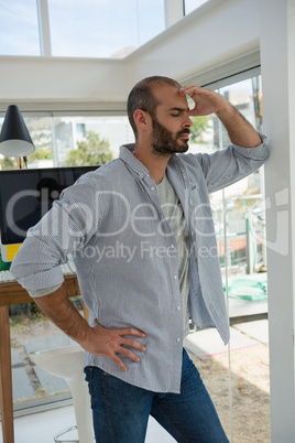 Tensed designer standing by wall