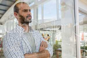 Thoughtful designer with arms crossed seen through glass