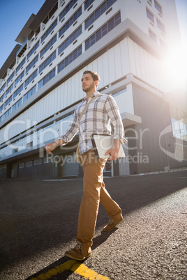 Man holding laptop while walking on city street