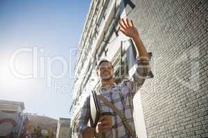 Man holding disposable cup gesturing while walking by building in city